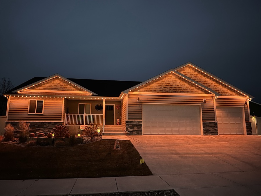 Single-story home with warm amber roofline lighting against a deep blue evening sky